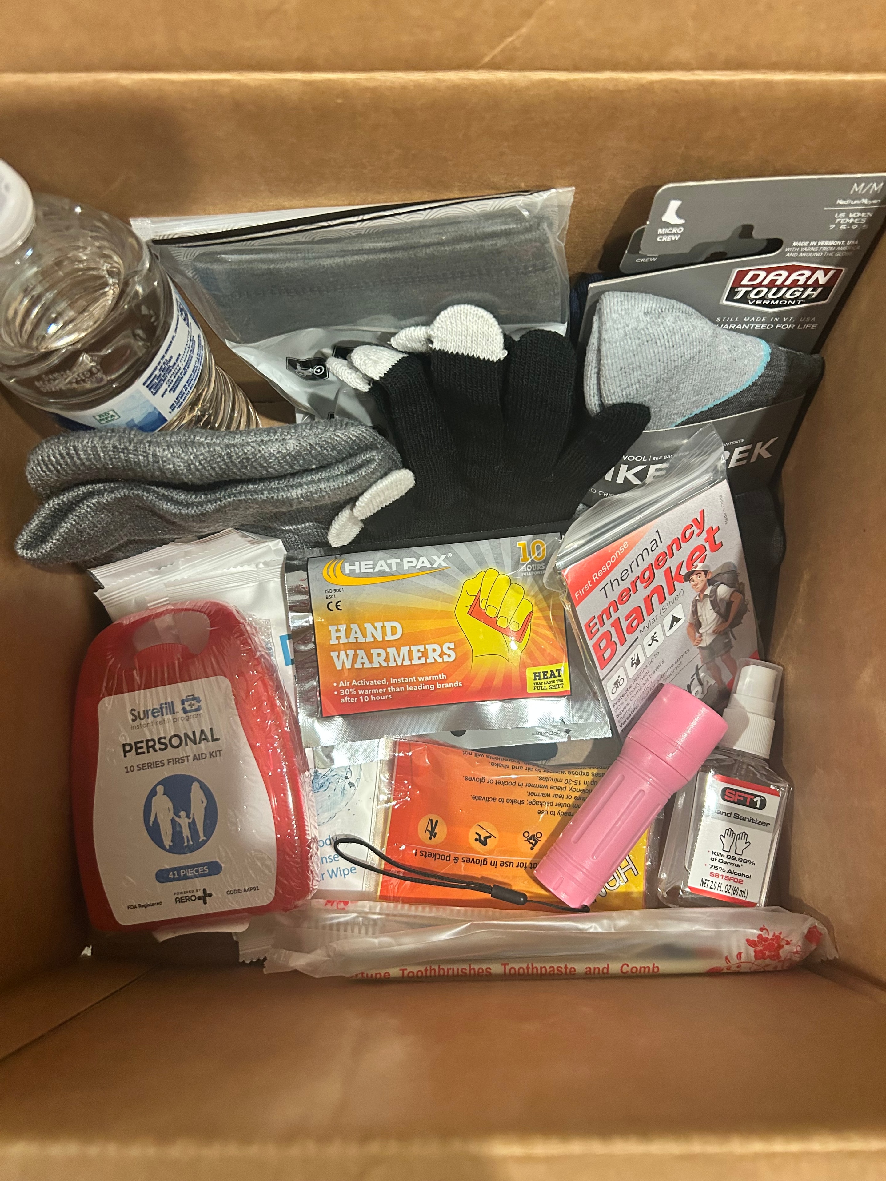 Care package contents including socks, gloves, hand warmers, first aid kit, flashlight, and hygiene items