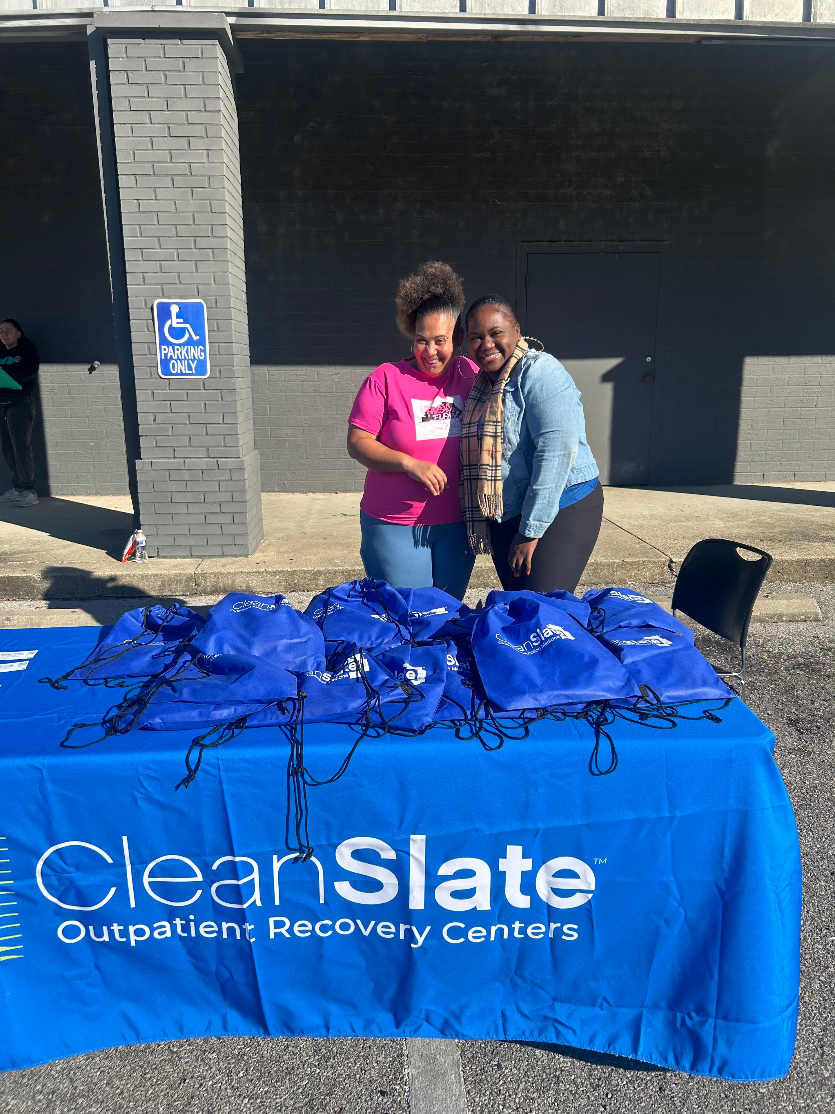 Two people at the ClearSlate Outpatient Recovery Centers booth with blue resource bags at Operation Warm Hearts