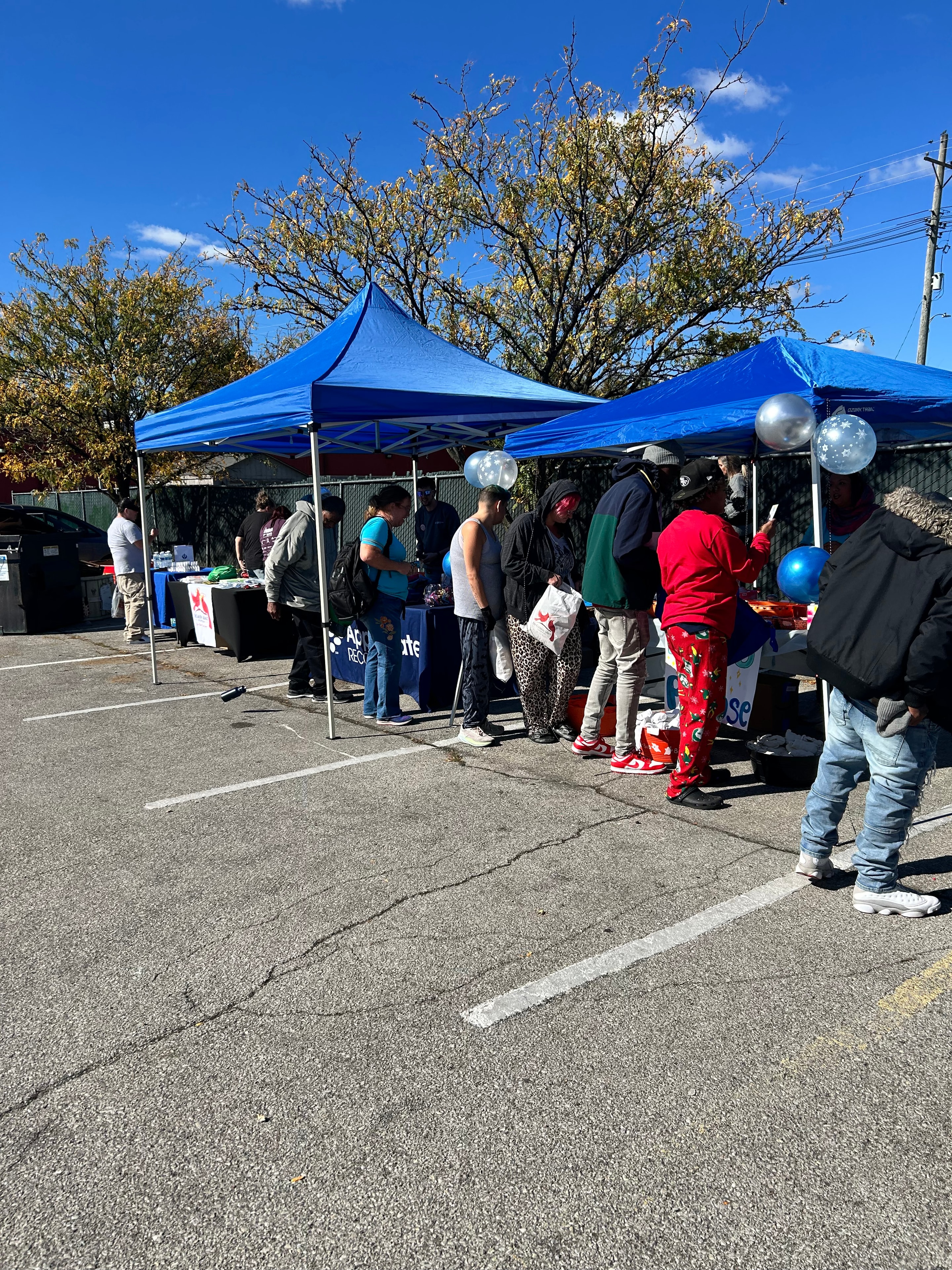 Community members gathered under the blue canopy tent at Operation Warm Hearts