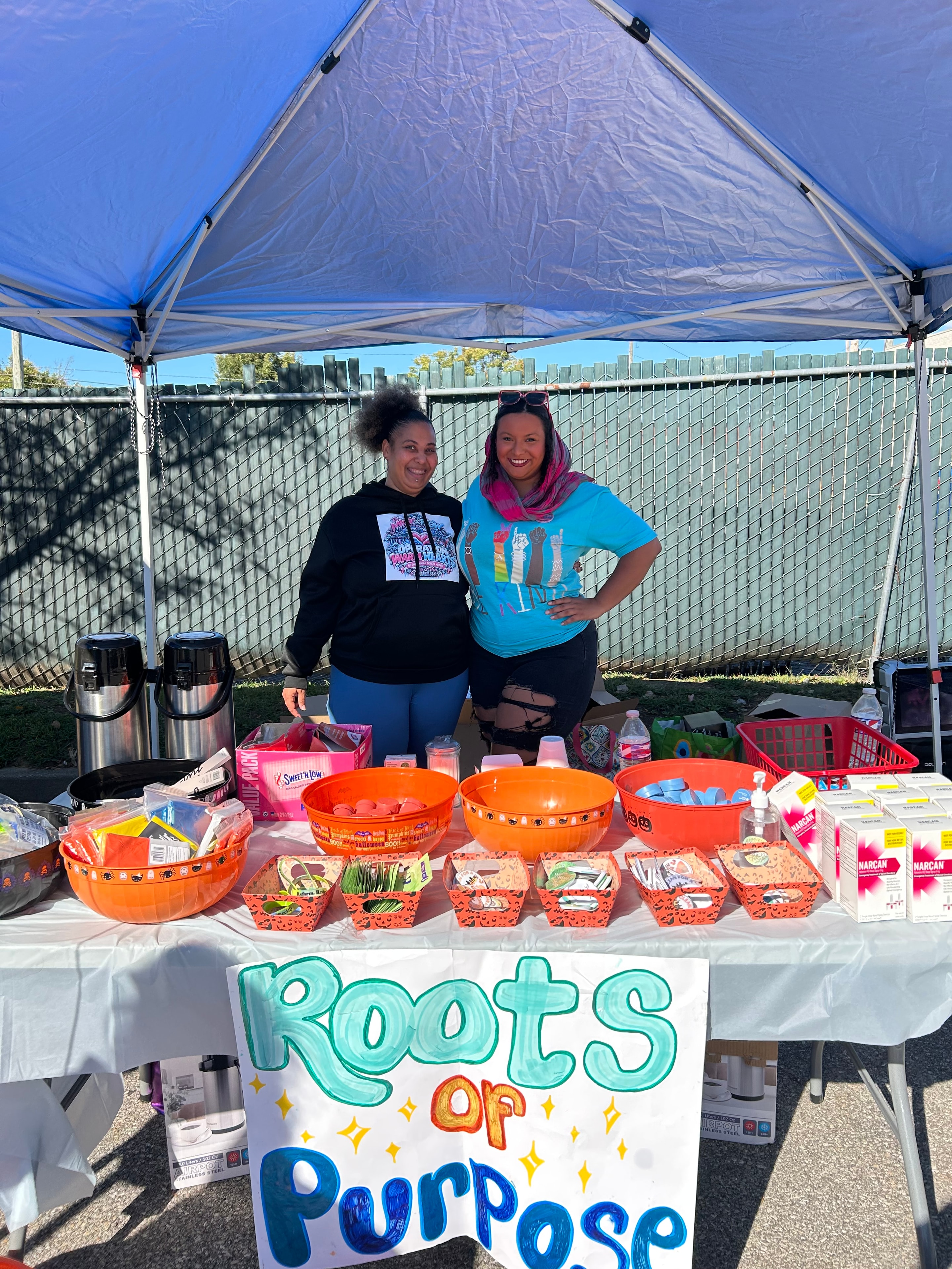 Two volunteers at the Roots of Purpose booth with orange survival kits at Operation Warm Hearts