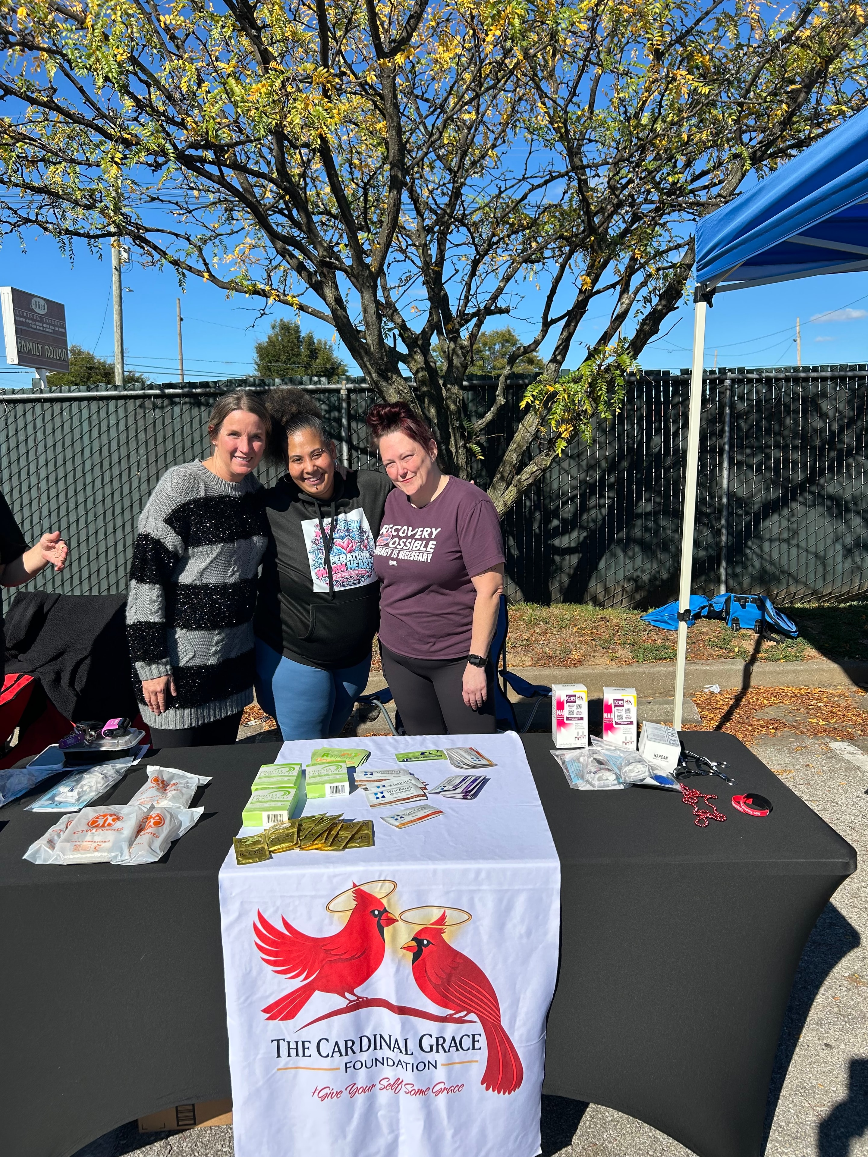 Three people at The Cardinal Grace Foundation booth at Operation Warm Hearts